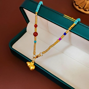 Detail of gold-plated calabash pendant with colorful beads in a dark green box