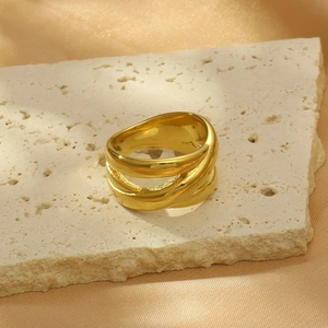 Dettaglio macro di un ampio anello intrecciato placcato oro 18k su pietra travertino