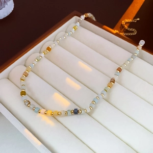 Macro shot of colorful square beads and golden spacers on a pearl necklace in a box
