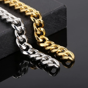 Detail of silver and gold Cuban link chains on a black box with visible metal clasps