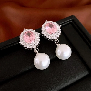 Detailed close-up of pink gemstone earrings with diamond halo and hanging white pearl