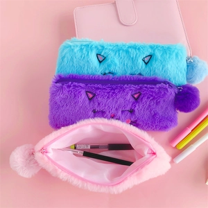 Three colorful plush cat pencil cases in blue, purple, and pink with fluffy pom-pom charms