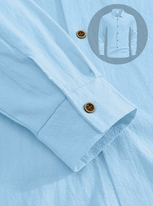 Detail of light blue linen shirt sleeve showing stitching and vintage brown buttons