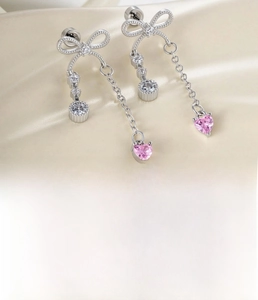 Detailed shot of silver bow tassel earrings with pink heart zircon and titanium steel chains