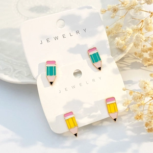 Bunte Bleistift-Ohrstecker aus Emaille auf einer schlichten Schmuck-Präsentationskarte