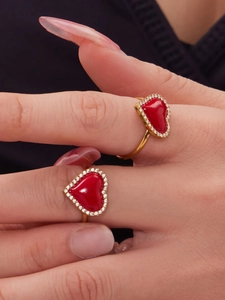 Gros plan de deux bagues dorées avec oxydes de zirconium cœur rouge sur une main