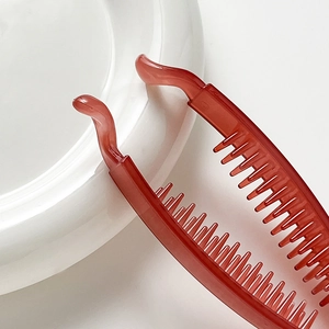 Glossy red banana hair clip with large teeth for thick hair shown on a minimalist background
