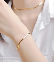 Close-up of a high-shine golden flat snake bone chain bracelet and matching necklace