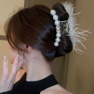 Detail of elegant hair claw clip with large pearls, rhinestones and white feathers