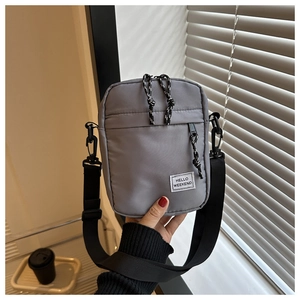 Detail view of a gray Oxford cloth crossbody bag featuring a Hello Weekend label and rope zipper