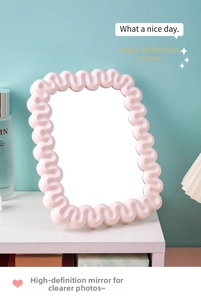 Detailed close-up of pink wave-edged desktop makeup mirror with clear high-definition glass