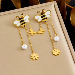 Elegant gold bee tassel earrings with flowers and pearls on professional display