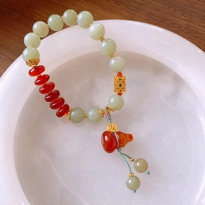 Detail of beaded bracelet with green jade beads, red agate, and golden lucky gourd charm