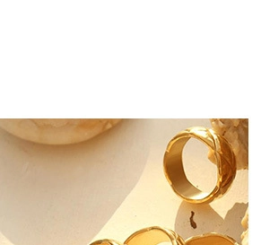 Macro shot of gold metallic ring with diamond pattern texture on light stone surface