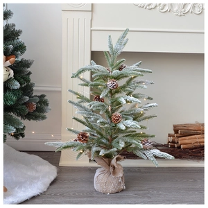 Detail of a snow-flocked desktop Christmas tree with pine cones and burlap base