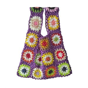 Close-up of handmade crochet handbag featuring colorful floral patterns on purple knit