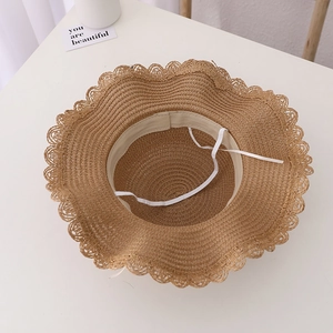 Close-up of brown straw hat interior featuring adjustable white strap and sweatband detail