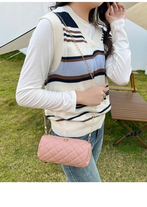 Outdoor model shot of pink cylindrical crossbody bag with diamond quilting and chain strap