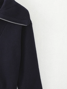 Macro detail of navy blue knit sweater featuring a silver metal zipper and thick texture