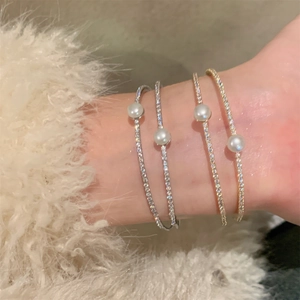 Close-up of stacked gold and silver pearl bracelets with zircon pavé on female wrist
