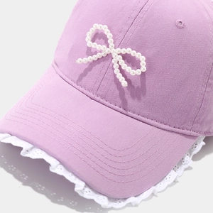 Detail of lavender baseball cap featuring white lace trim and handmade pearl bow