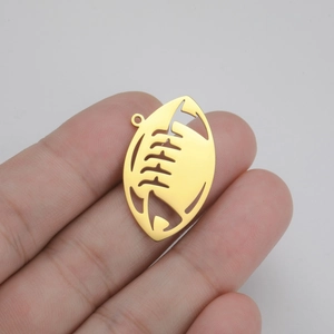 Macro shot of a golden hollow rugby-shaped pendant held by fingers for detail