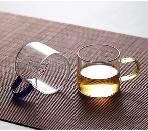 Close-up of heat-resistant borosilicate glass tea cups with colored handles on a bamboo mat