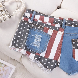 Dettaglio di pantaloncini in denim strappati con stampa bandiera USA e orlo sfilacciato