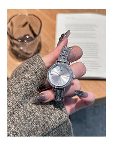 Detail of silver women watch with crystal bezel and steel strap held by elegant hand