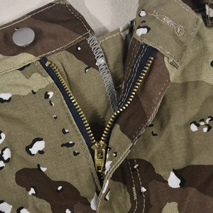 Détail macro du tissu sergé camouflage avec fermeture éclair et bouton en métal