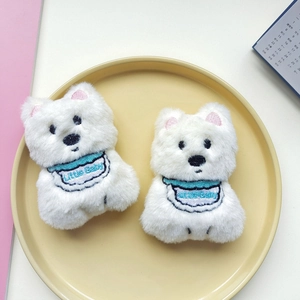 Close-up of two white plush puppies in a bowl with Little Baby embroidered bibs
