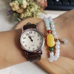 Detail showing quartz watch with brown leather strap and beaded bracelets on wrist