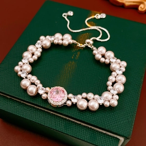 Detail of elegant pearl bracelet featuring a pink gemstone and zircon on a green jewelry box