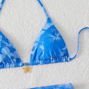 Detail view of blue tropical floral bikini top with a gold-tone petal pendant
