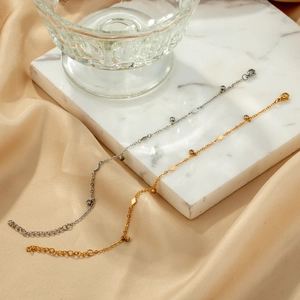 Elegant gold and silver thin link bracelets with diamond charms on marble background