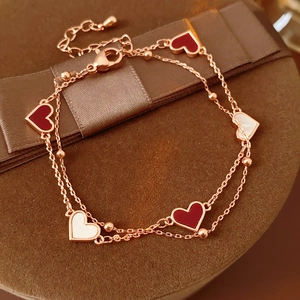Détail d'un bracelet double rang en or rose avec des cœurs en nacre rouge et blanc