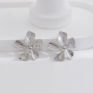 Elegant silver flower earrings with pleated texture on white geometric steps