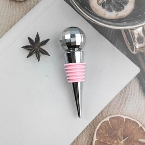 Pink disco ball wine stopper with zinc alloy base on a white notebook background