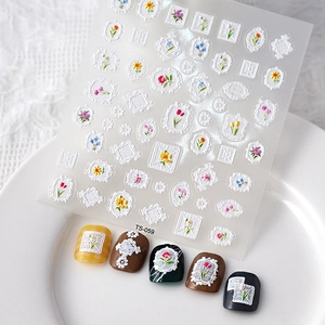 Close-up of 5D white lace relief nail art stickers with delicate colorful floral patterns