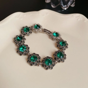 Close-up of vintage flower bracelet with green gemstones and sparkling rhinestones