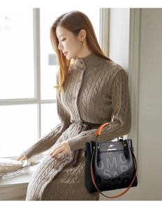 Detail of black embossed leather tote featuring orange handles and branded kangaroo logo