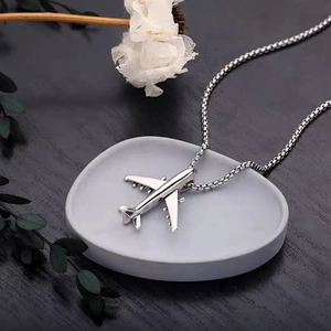 Detail shot of silver fighter plane pendant with box chain on a white display plate
