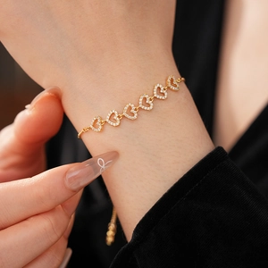 Gros plan d'un bracelet doré en forme de cœur avec zircons porté élégamment au poignet