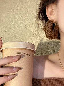 Detail of large brown knit hoop earrings with textured crochet twist on a model