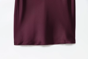 Close-up of the smooth burgundy satin hemline with elegant high-shine silk texture