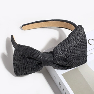 Detail of black woven straw bow headband with khaki lining on a fashion magazine