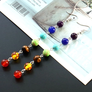 Macro detail of seven colorful chakra stone beads on silver bohemian tassel earrings