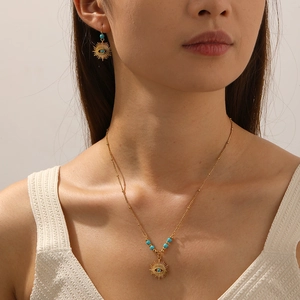 Detail of model wearing 18k gold-plated sun-eye jewelry set with turquoise stone