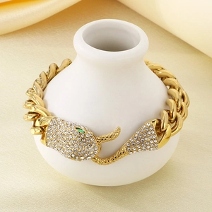 Detailed macro of gold Cuban link bracelet with diamond-encrusted snake head and green eyes