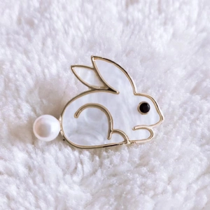 Detailed macro view of white mother-of-pearl rabbit brooch with gold trim and pearl tail